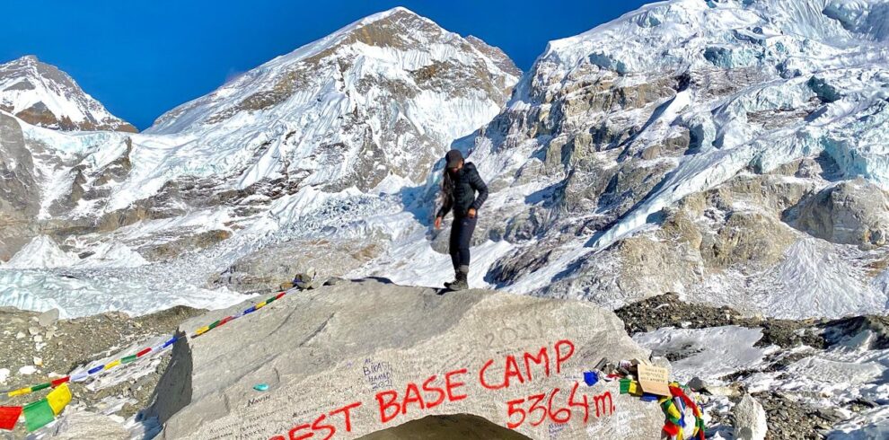 Trekker standing at Everest Base Camp with Mount Everest towering in the background