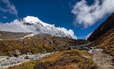 Mountain trail with rocky terrain and distant snow-capped peaks en route to Tsho Rolpa Lake, Nepal