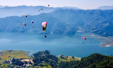 Paraglider soaring over Phewa Lake with the Annapurna mountain range in the background, Pokhara, Nepal