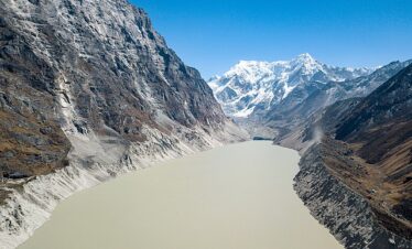 Tsho Rolpa Glacial Lake surrounded by rugged Himalayan peaks and rocky terrain