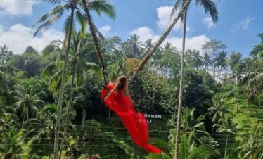 Person swinging high above the jungle canopy on the famous Bali Swing attraction