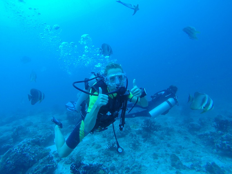 Traveler snorkeling in the coral-rich waters of the Maldives surrounded by marine life