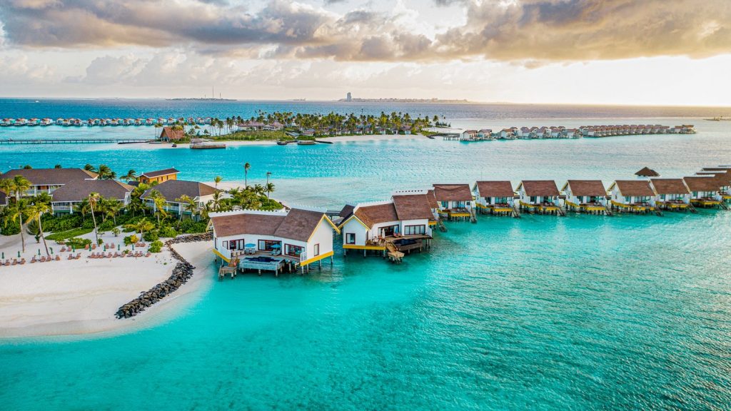 Water villas and aerial view of the full island of SAii Lagoon Maldives with surrounding blue lagoon