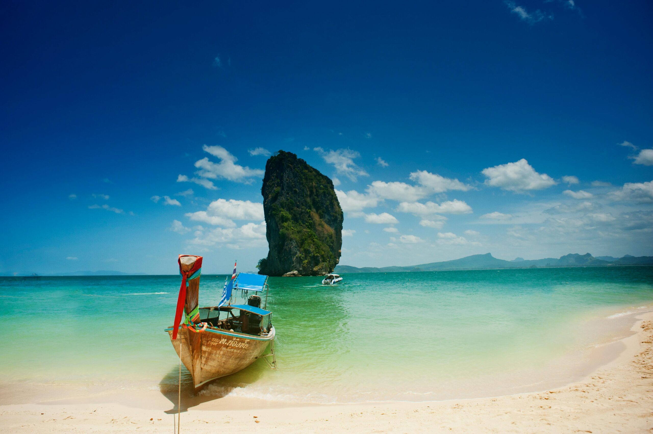 Pristine sandy beach with turquoise waters and palm trees along the coastline in Thailand